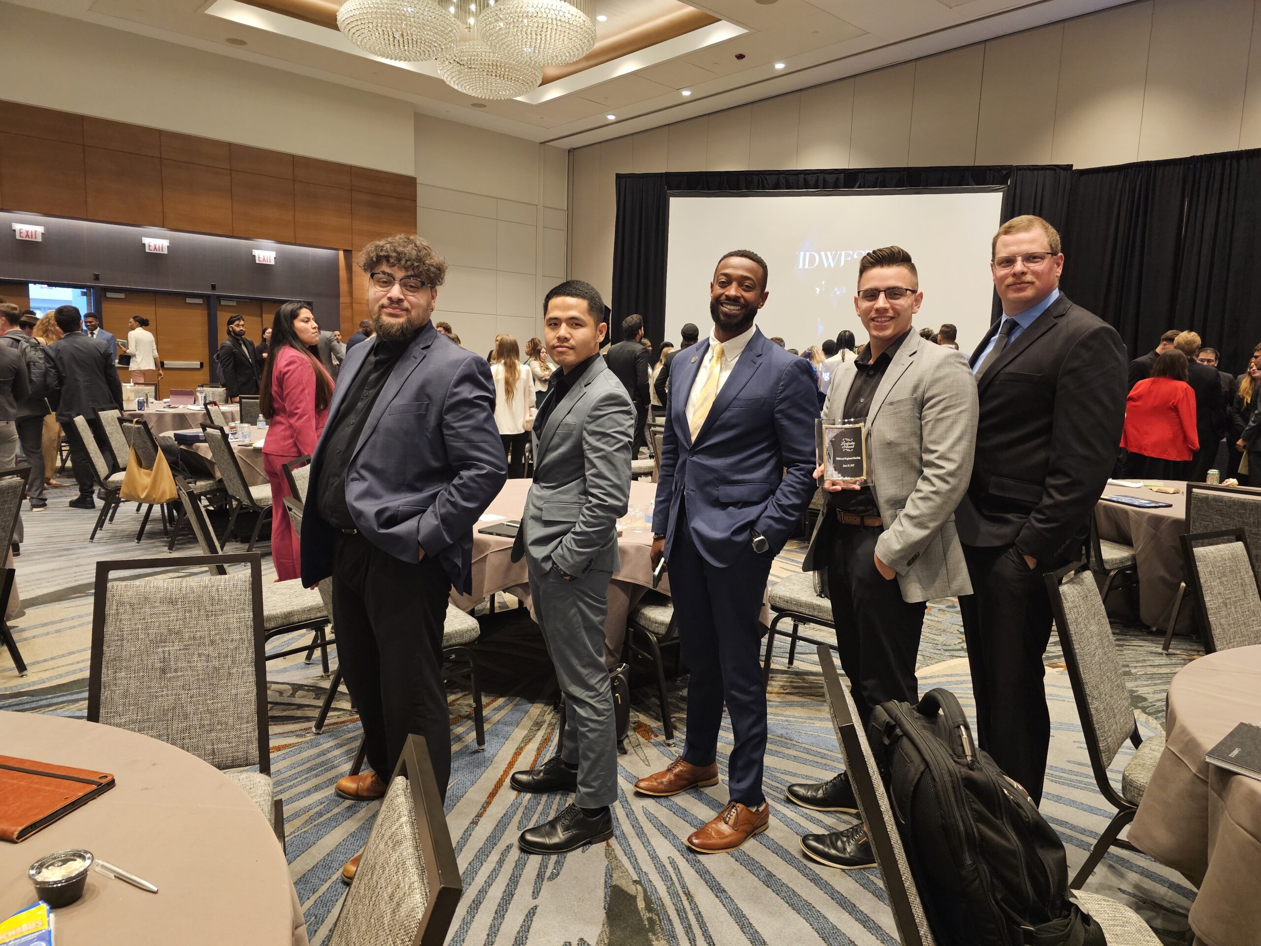 A group of five professional men in suits posing at a business awards gala or conference, illustrating industry recognition and success.